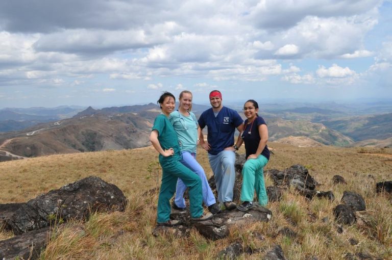 Four students in scrubs standing on a hilltop